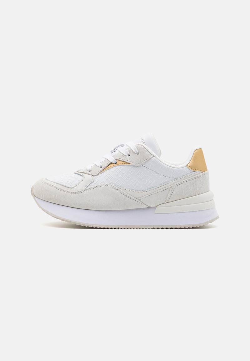 Chaussures de sport blanches et gris clair avec un dessus texturé, des accents en suède et un détail doré subtil sur le talon. Semelle blanche rembourrée.