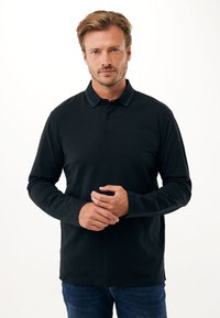 Polo a maniche lunghe in cotone nero con colletto caratterizzato da un sottile accento rigato. La vestibilità è comoda con orlo dritto.