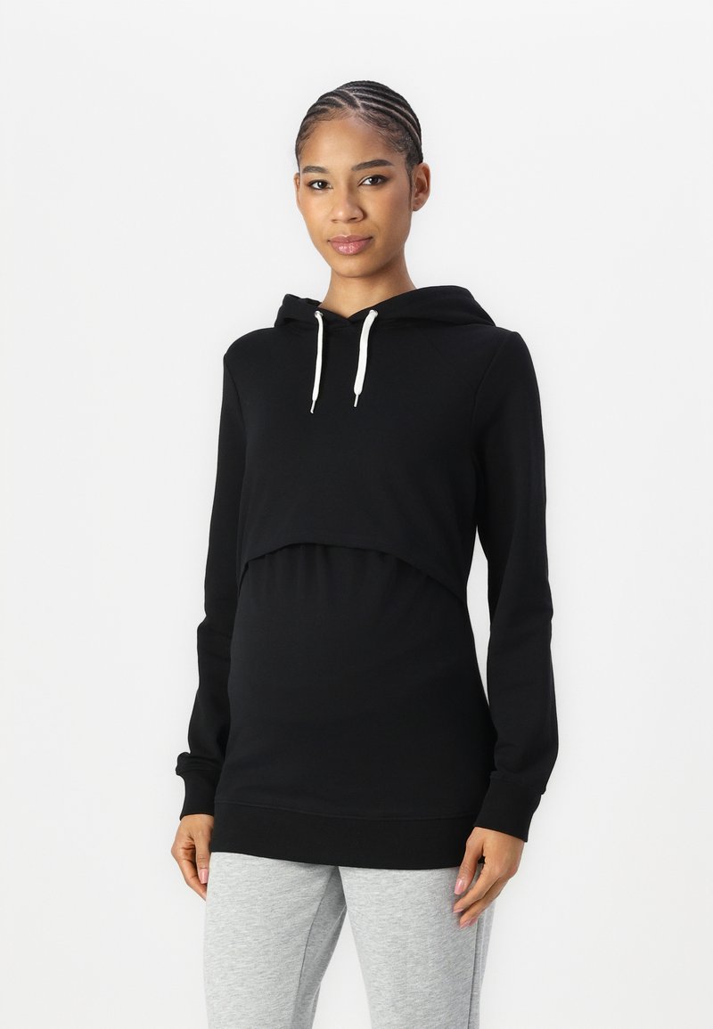 Black hoodie with a cropped design, drawstring, and long sleeves. Paired with light grey tapered pants for a casual look.