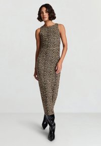 Leopardenmuster-Kleid in Beige und Schwarz, figurbetontes Design, ärmellos, reicht bis zur Mitte der Wade, kombiniert mit glänzenden schwarzen kniehohen Stiefeln.