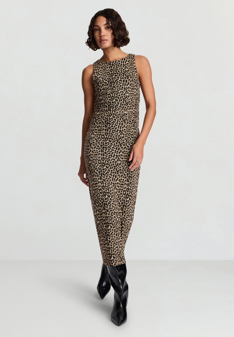 Leopardenmuster-Kleid in Beige und Schwarz, figurbetontes Design, ärmellos, reicht bis zur Mitte der Wade, kombiniert mit glänzenden schwarzen kniehohen Stiefeln.