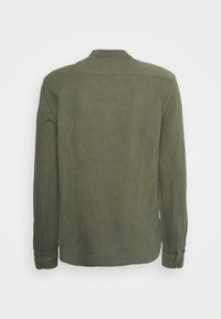 Camicia a maniche lunghe di colore verde oliva, realizzata in tessuto texturizzato. Presenta un colletto a punta e polsini con bottoni, con un design della parte posteriore dritta.