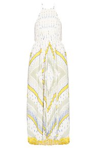 Robe maxi blanche à fines bretelles, avec des motifs géométriques et floraux jaunes, bleus et verts, et une jupe plissée.