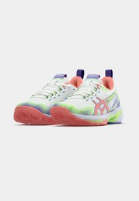 Λευκά αθλητικά παπούτσια με επάνω μέρος από δίχτυ, ροζ και πράσινα διακοσμητικά στοιχεία, μοβ ταμπελάκια στη φτέρνα και υφασμένο λαστιχένιο πέλμα με ζιγκ ζαγκ μοτίβο.