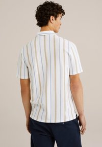 Polo de manga corta en blanco con rayas verticales en azul claro y beige. Tejido texturizado; cuello clásico; corte ligeramente holgado.