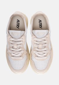 Sneaker bianche e beige con design in pelle perforata, lacci testurizzati, suola in gomma spessa e branding in rilievo sulla linguetta.