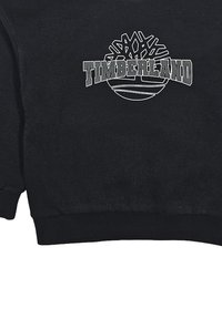 Felpa nera in tessuto misto cotone con logo Timberland e grafica dell'albero in bianco. Le maniche e l'orlo a coste aggiungono texture.