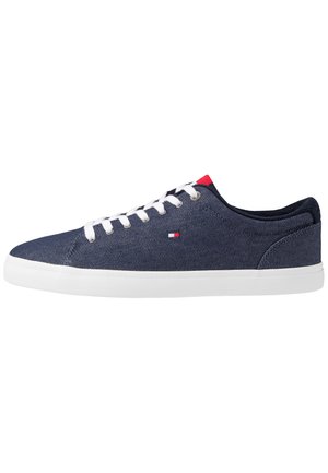 Niski granatowy sneaker z białymi sznurowadłami, białą podeszwą, małym czerwono-białym logo po boku i czerwonym akcentem na języku.