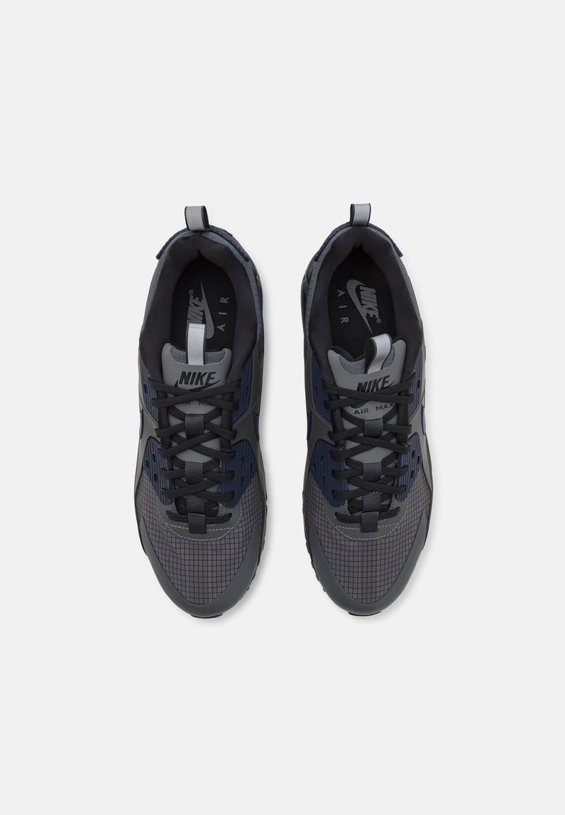 Baskets Nike Air Max en gris foncé et bleu marine, avec des textures en maille, des motifs en grille et des lacets noirs. Comprend des poignées pour un enfilage facile.