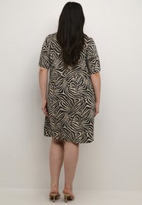 Robe à manches courtes, longueur genou, avec un motif zèbre noir et beige, fabriquée dans un tissu léger avec une coupe décontractée et un col rond.