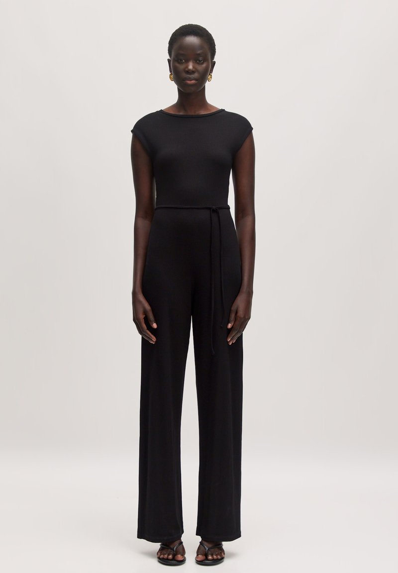 Schwarzer gerippter Jumpsuit mit kurzen Ärmeln, tailliertem Oberteil, weit geschnittenen Hosenbeinen und gebundenem Taillendetail, gefertigt aus weichem, dehnbarem Material.