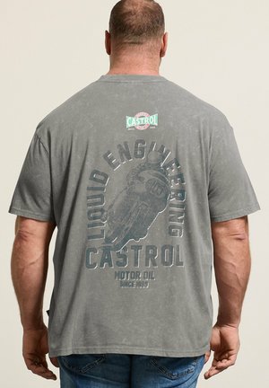 Hombre que lleva una camiseta gris desgastada de Castrol motor oil con un gráfico de motocicleta y texto "Liquid Engineering" visto desde atrás.