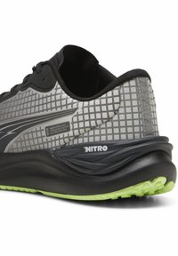 Juodas ir pilkas sportinis batas su raštuotu tinkleliu, vandeniui atsparia medžiaga ir kalkių žalios spalvos padu, kuris užtikrina geresnį sukibimą ir stabilumą.