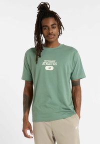 Grøn bomulds t-shirt med korte ærmer, med et hvidt "New Balance Athletics" logo i midten og afslappet pasform.
