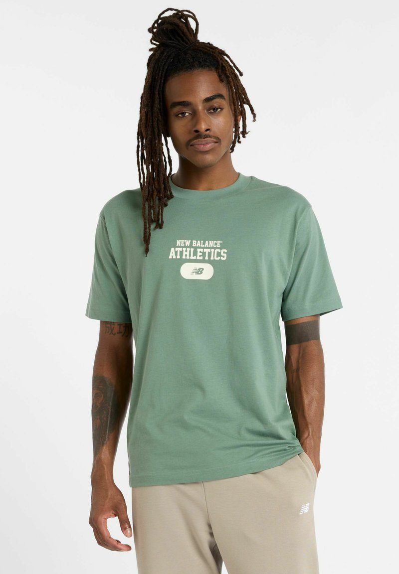 Grøn bomulds t-shirt med korte ærmer, med et hvidt "New Balance Athletics" logo i midten og afslappet pasform.