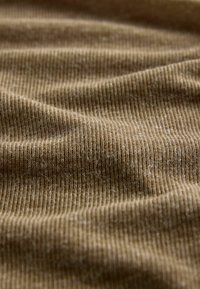 Artiškinis artimasis rudos juostelės audinys su minkštais raukšlėmis ir matomomis tekstūros detalėmis.