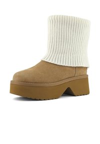 Botines de ante en tono marrón claro con un puño de tejido de punto blanco acanalado, suela de plataforma marrón gruesa y forma de cuña ligeramente pronunciada, con un acabado texturizado.