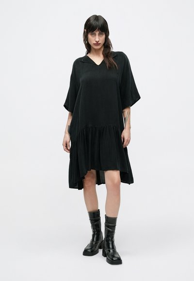 Μαύρο βαμβακερό φόρεμα με V λαιμόκοψη, φαρδιά μανίκια και σούρα στο κάτω μέρος, με ρέουσα σχεδίαση και ελαφρώς πιο μακρύ πίσω μέρος.
