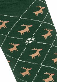 Chaussettes vertes avec une texture côtelée, présentant un motif répété de rennes brun clair sur un fond à carreaux en diamant avec des accents blancs.