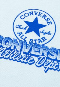 Μπλε σχεδιασμός με σχέδιο πάνω σε ανοιχτό μπλε ύφασμα που περιλαμβάνει τη λέξη "CONVERSE," ένα αστέρι και τη φράση "Athletic Dept." με έντονα γράμματα. Απαλή υφή με casual στυλ.