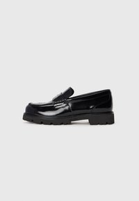 Schwarzer Lackleder-Lederschuh mit dicker Gummisohle und Mokassin-N�ähten, präsentiert auf einem schlichten weißen Hintergrund.