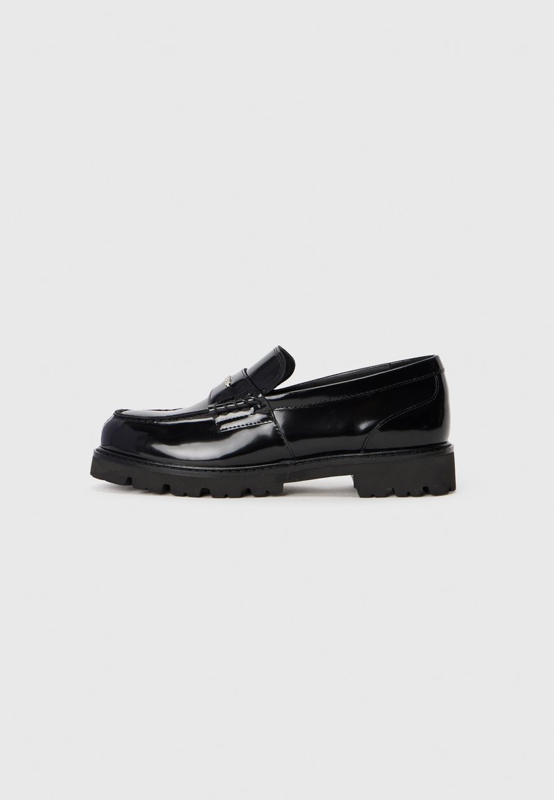 Schwarzer Lackleder-Lederschuh mit dicker Gummisohle und Mokassin-Nähten, präsentiert auf einem schlichten weißen Hintergrund.