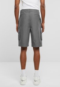 Shorts cargo gris avec poches latérales, une coupe décontractée et un tissu légèrement texturé. Dispose de poches arrière cousues et d'une taille mi-haute.
