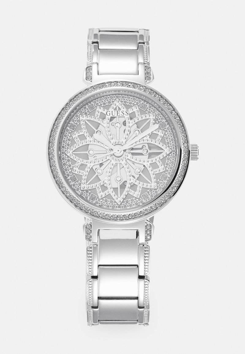Sølvklokke med en blomsterdekorert urskive, utsmykket med krystaller, og et polert metalarmbånd med lenker og dekorative detaljer.