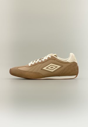 Baskets basses marron et beige avec lacets blancs et le logo double diamant Umbro sur le côté sur fond uni.
