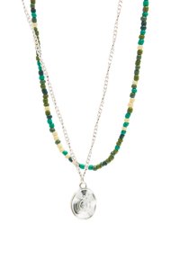 Kralenketting met groene, blauwe en gele vierkante kralen, gelaagd met een zilveren ketting en een ronde hanger met een spiraalontwerp.