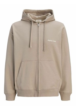 Sweat à capuche beige zippé avec poches avant, cordon de serrage à la capuche, poignets et ourlet côtelés, et petit texte blanc « Originals Studio » sur la poitrine gauche.