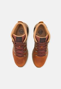 Zapatos de senderismo de piel marrón con un diseño texturizado, malla burdeos de contraste, ojales de metal y cuellos acolchados. Suelas de goma duraderas.