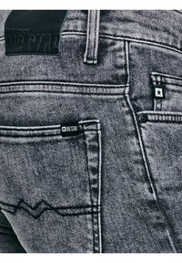 Hallkaadrid hallidest teksapükstest, mis näitavad tagataskuid, õmbluste detaile ja Big Star kaubamärgi silte vöökohal ja taskul.