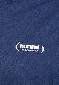 Námořnická modrá bavlněná tričko s bílým logem "hummel" a textem "SPORTSWEAR". Materiál je vroubkovaný s hladkým povrchem.