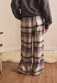 Plaid wide-leg pants feature a beige and gray color scheme with black and brown accents. Made from soft fabric, they have a relaxed fit.