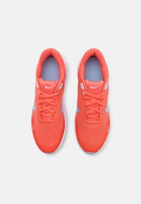 Chaussures de course Nike en maille corail vif, avec des accents bleu clair, embout rond, semelle plate, dotées d'un dessus texturé et d'un système de laçage traditionnel.