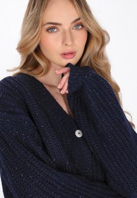 Cardigan lavorato a maglia in navy con un motivo testurizzato, caratterizzato da scollo a V, maniche lunghe e un singolo dettaglio con bottone argentato.