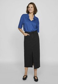 Blue short-sleeved button-up shirt with collar, paired with a black fabric maxi skirt featuring a front slit. Black flat shoes complete the look.
