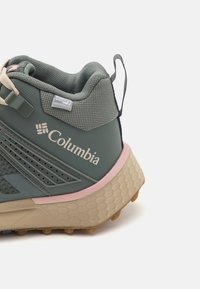 Wodoodporne buty trekkingowe Columbia w odcieniu szarym z różowymi akcentami. Posiadają teksturowaną cholewkę, wsparcie pięty oraz ruggedową podeszwę zapewniającą przyczepność.