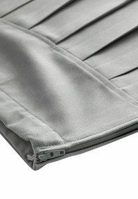 Housse de coussin en tissu gris avec un design plissé, dotée d'une fermeture éclair discrète et d'une texture lisse. Style simple et fonctionnel.