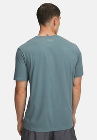 Trumpas rankovėmis marškinėliai iš švelnaus mėlyno audinio. Turi apvalų iškirpimą ir mažą logotipą viršutiniame nugaros dalyje. Minkšta tekstūra, įprastas iškirpimas.