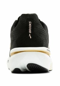 Zapatilla de running negra con parte superior texturizada, franja de acento dorada y media suela blanca. Presenta un logo en el talón y una suela de goma para mejorar la tracción.