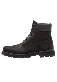 Czarne wodoodporne buty zamszowe i skórzane z gumową podeszwą, wiązane, z wyściełanym kostką. Zawierają logo z boku.