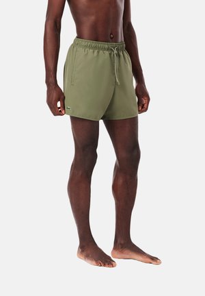Shorts de bain olive avec une taille élastique, fermeture à cordon et poches latérales. Ils présentent un petit logo brodé sur l'ourlet.