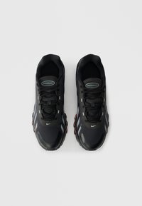 Para czarnych butów Nike Air Max z czerwonymi akcentami, widok z przodu, ustawionych obok siebie na jednolitym jasnym tle.