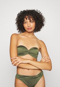 Grønt to-delt bikini med en stropless, tvinnet bandeau-overdel og høy midje-bunn med rynkede detaljer, laget av glatt stoff.