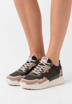 Sneakers stringati con un mix di materiali verde scuro, rosa e beige. Presentano un tessuto testurizzato, dettagli in suede e una robusta suola bianca.