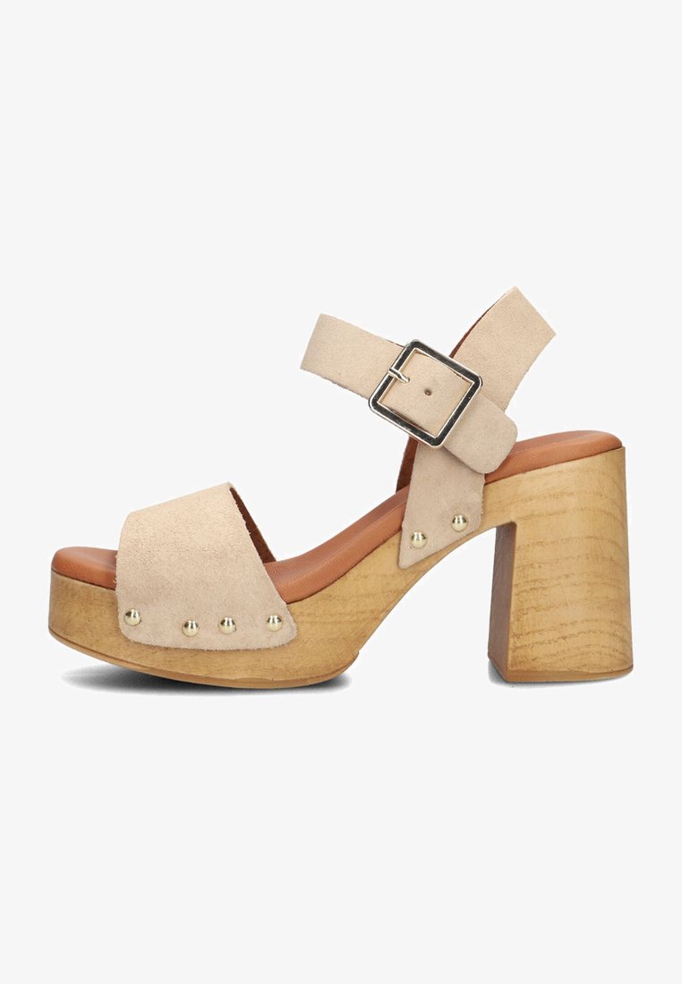 Beige suede platform sandals with a chunky wooden heel, featuring a buckled ankle strap and brass stud accents along the front.