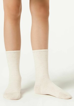 Calze di cotone a girocollo di colore beige chiaro con una texture a costine, caratterizzate da un design uniforme e da un risvolto nella parte superiore.