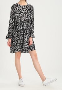 Musta kukkamekko pitkillä hihoilla, kootulla vyötäröllä ja hyväilevällä helmalla. Ainuttavat valkoiset kukat ja yhdistetty valkoisten tennareiden kanssa.